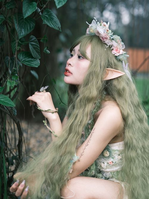 Free Fantasy-themed portrait of an elf woman with flower crown in a lush outdoor setting. Stock Photo