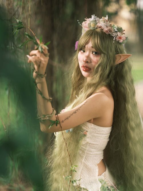 Free Elf-like woman with floral crown in ethereal forest environment, conveying mystical fantasy theme. Stock Photo