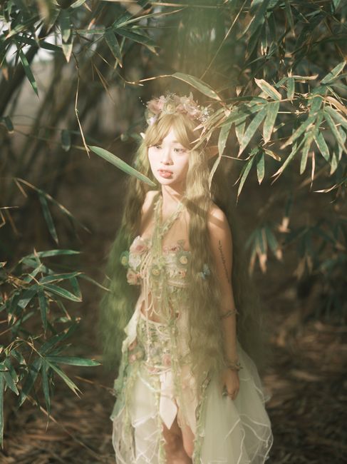 Fotomural Una mujer vestida de ninfa del bosque, rodeada de bambú, en un entorno místico.