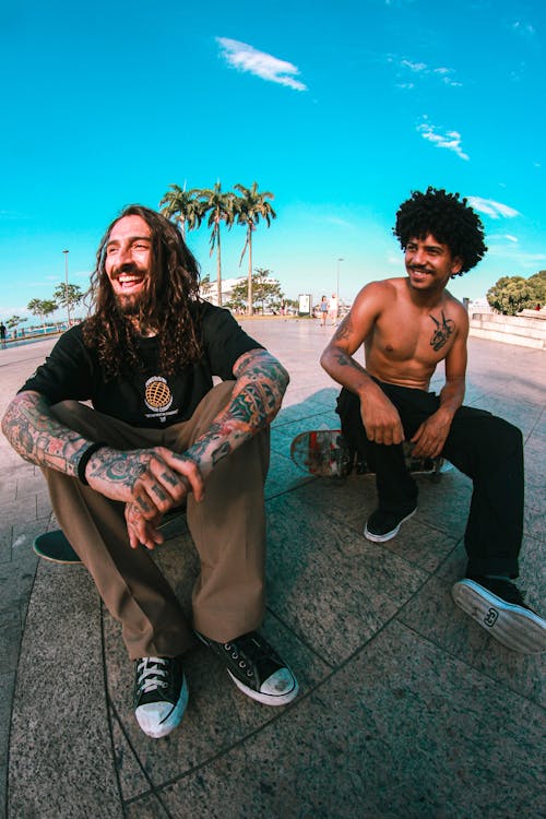 Smiling Men Sitting on Skateboards