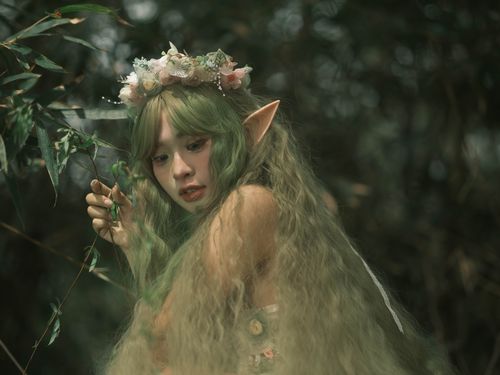 Free Enchanting portrait of an elf woman with green hair and floral crown in a forest setting. Stock Photo