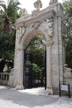 Intricately carved stone gate with foliage backdrop in daytime.