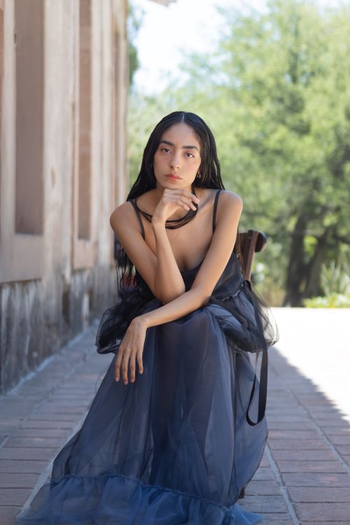 Free Woman in a dark dress sitting outdoors, exuding elegance and contemplation. Stock Photo