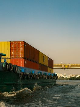 Industrial container ship navigating Saigon River under a clear sky with a cityscape in the background.