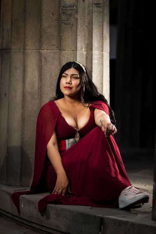 Free Woman in medieval red dress reflects in serene moment outdoors. Stock Photo