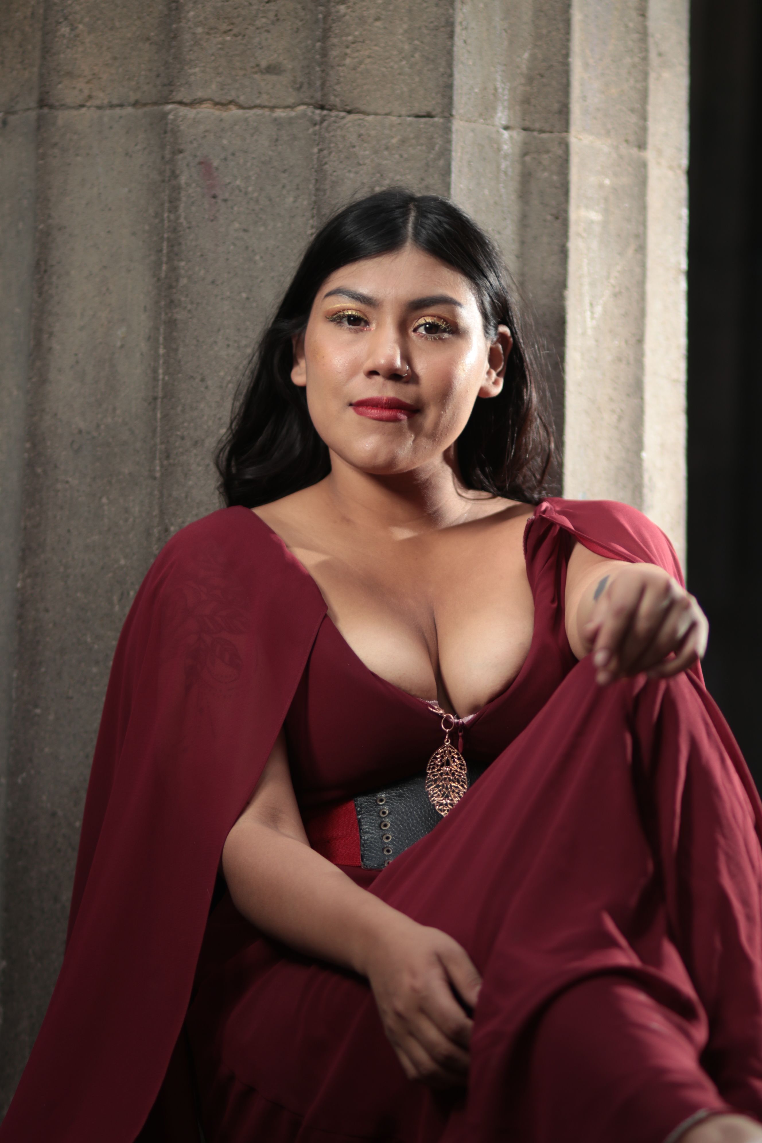 Fashionable woman posing elegantly in a red dress indoors.