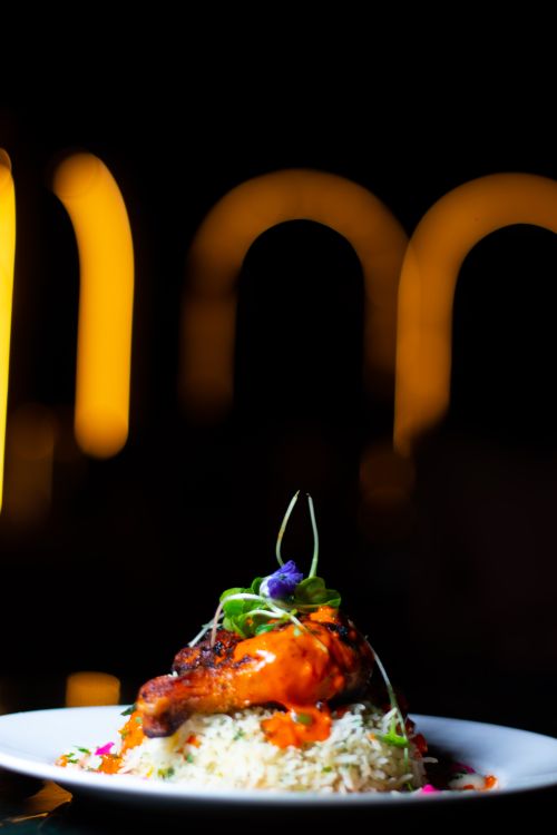 Free Exquisite tandoori chicken on a bed of herb rice garnished with vibrant edible flowers, showcasing modern Indian cuisine. Stock Photo