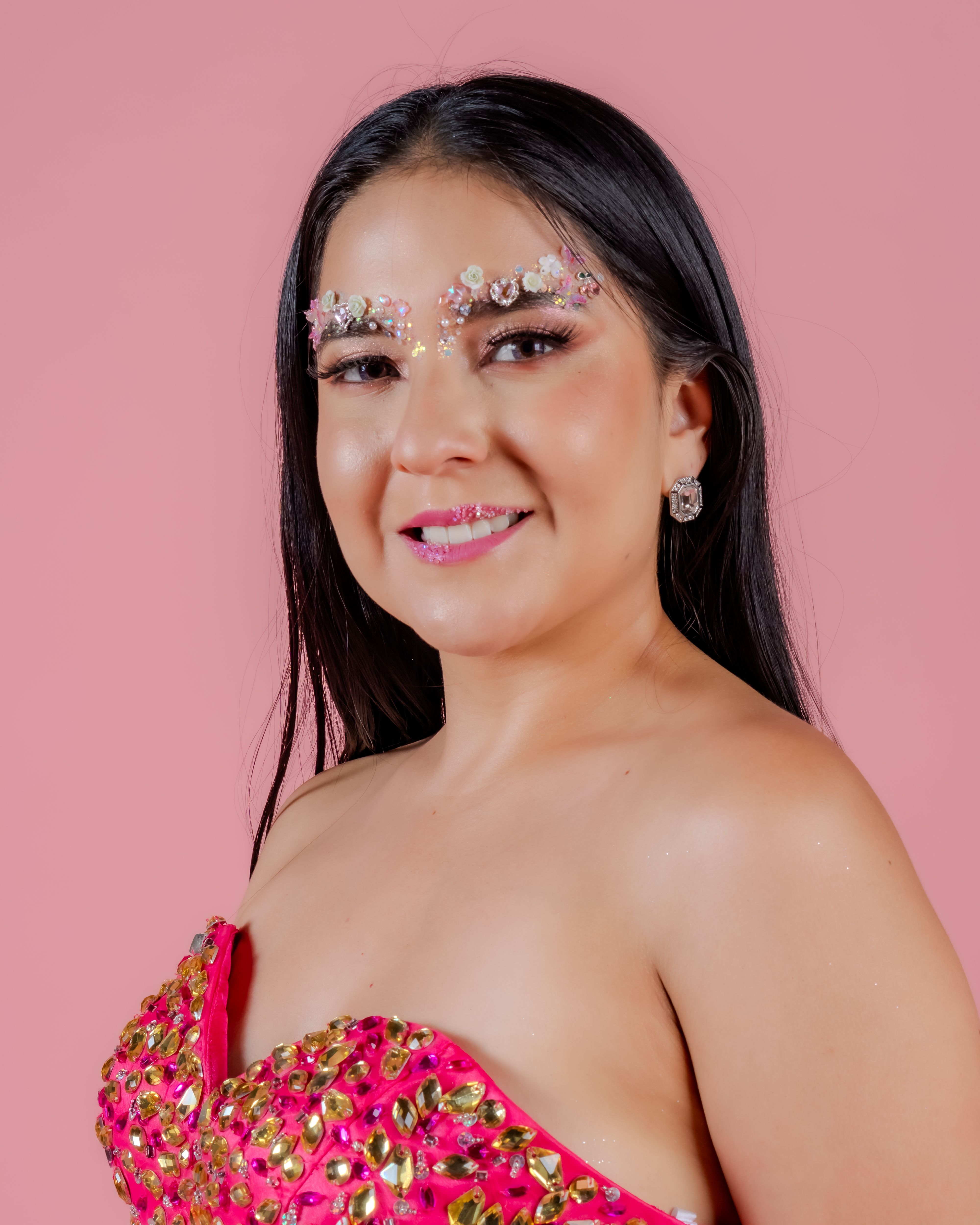 A stylish woman in a vibrant pink outfit posing gracefully on a soft pink background.