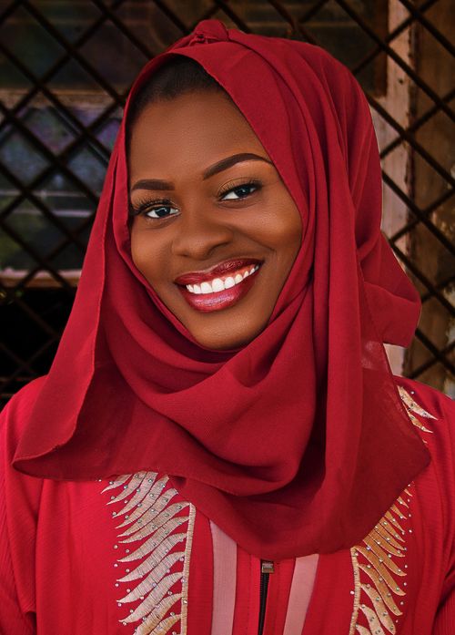 Free A smiling woman wearing a red hijab in a close-up portrait, exuding warmth and joy. Stock Photo
