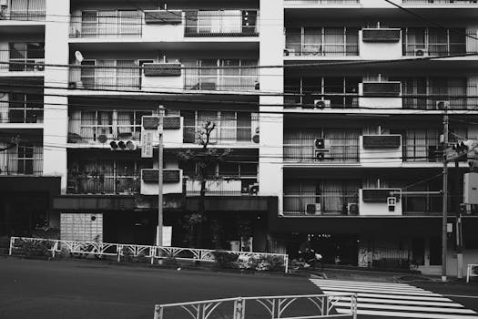 Black and white image capturing a residential building in Tokyo, Japan, reflecting urban life.