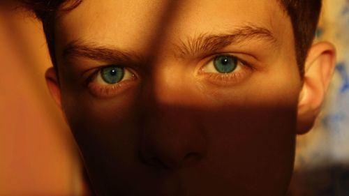Free A captivating close-up portrait emphasizing blue eyes partly in shadow. Stock Photo