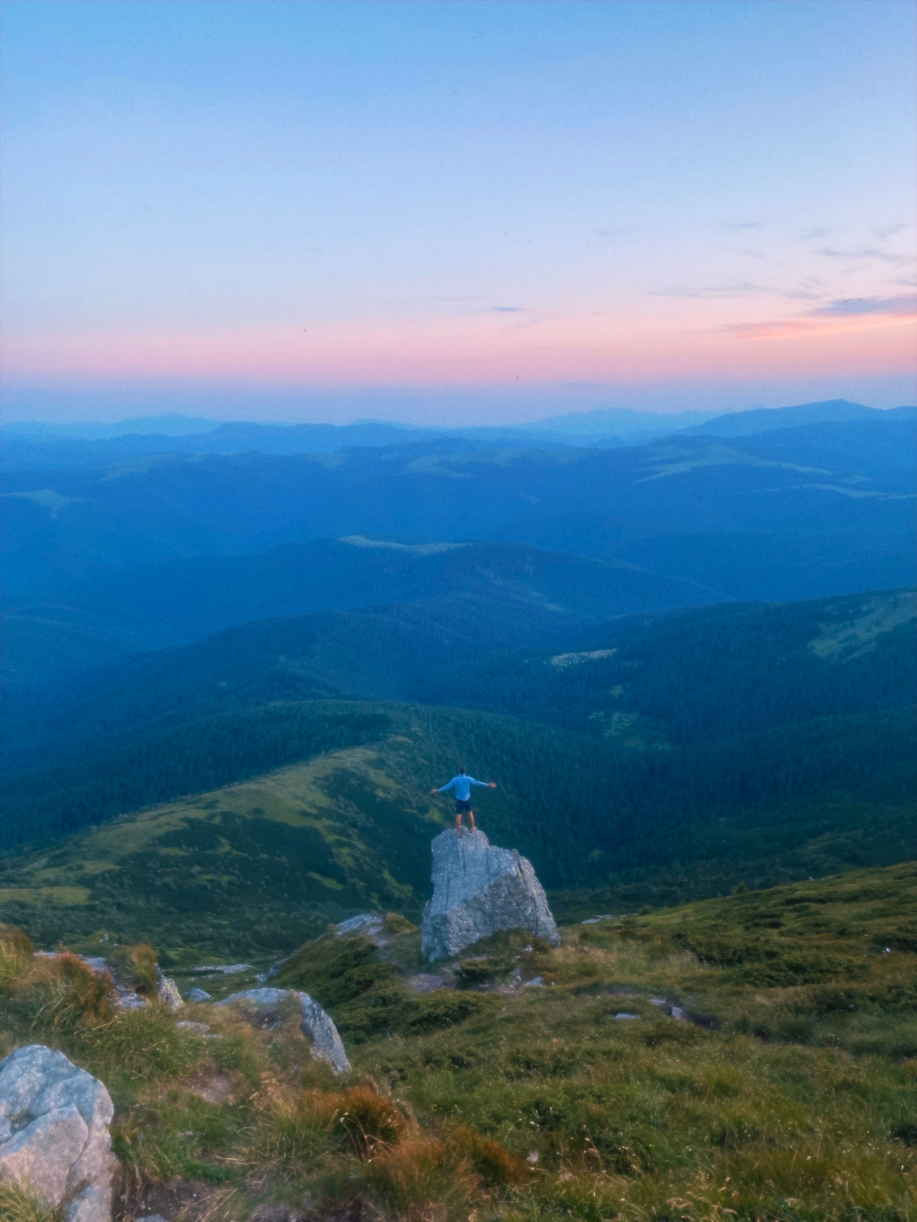 Adventurer Standing on Mountain Rock at Sunset · Free Stock Photo