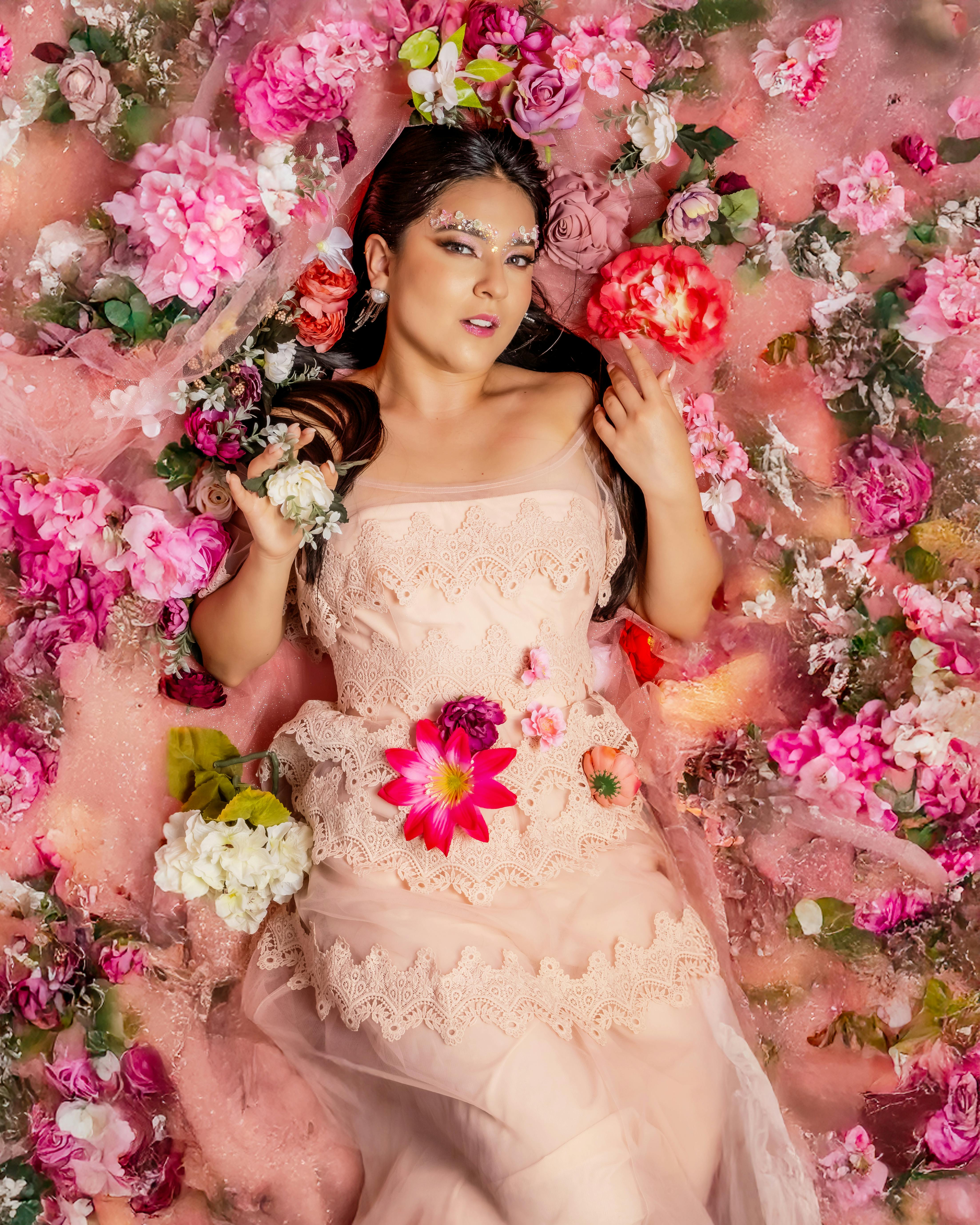 Gratis Graziosa donna circondata da vivaci fiori rosa, simbolo di potere e femminilità. Foto a disposizione