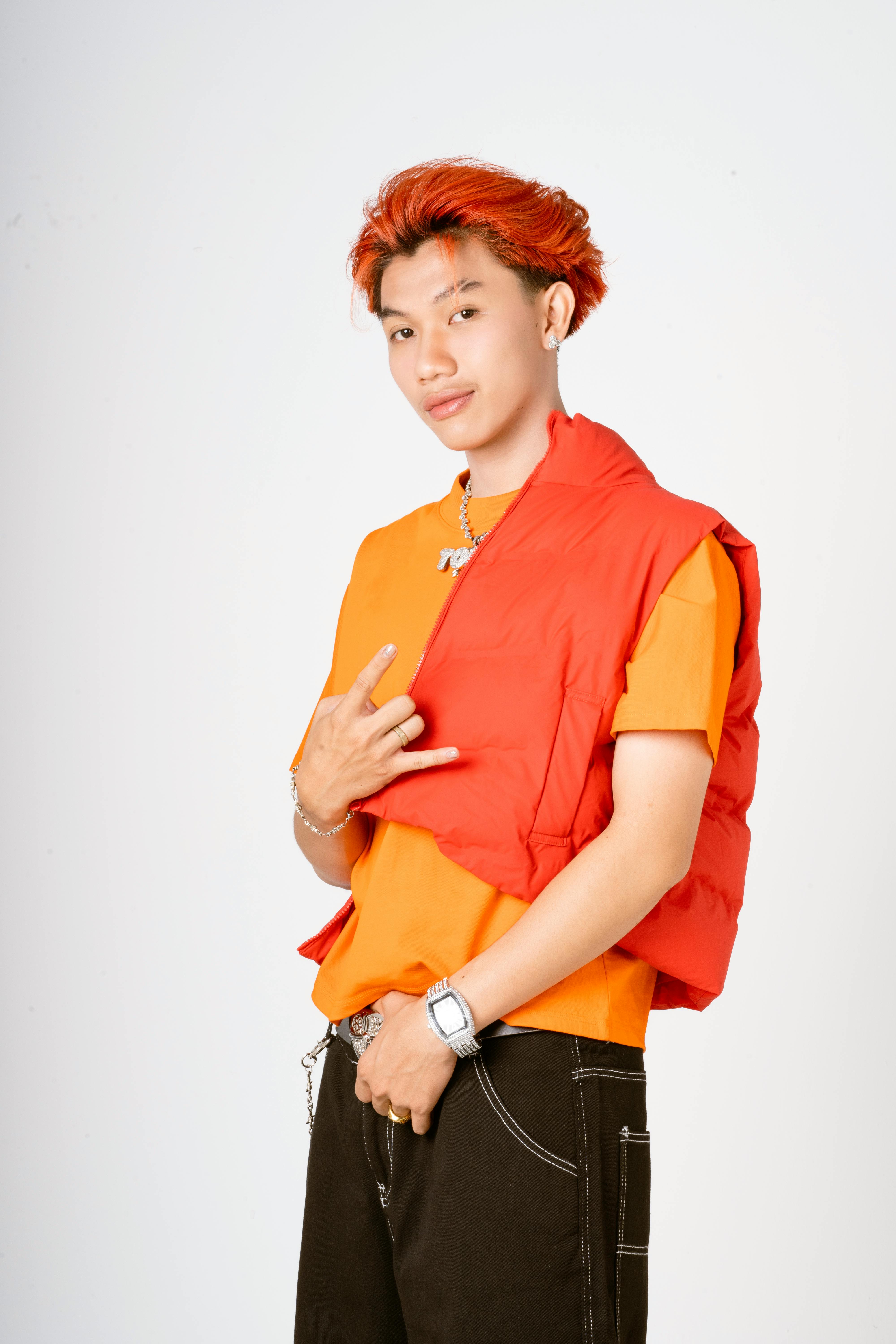Stylish young man posing with a confident smile in a colorful and casual outfit against a white background.