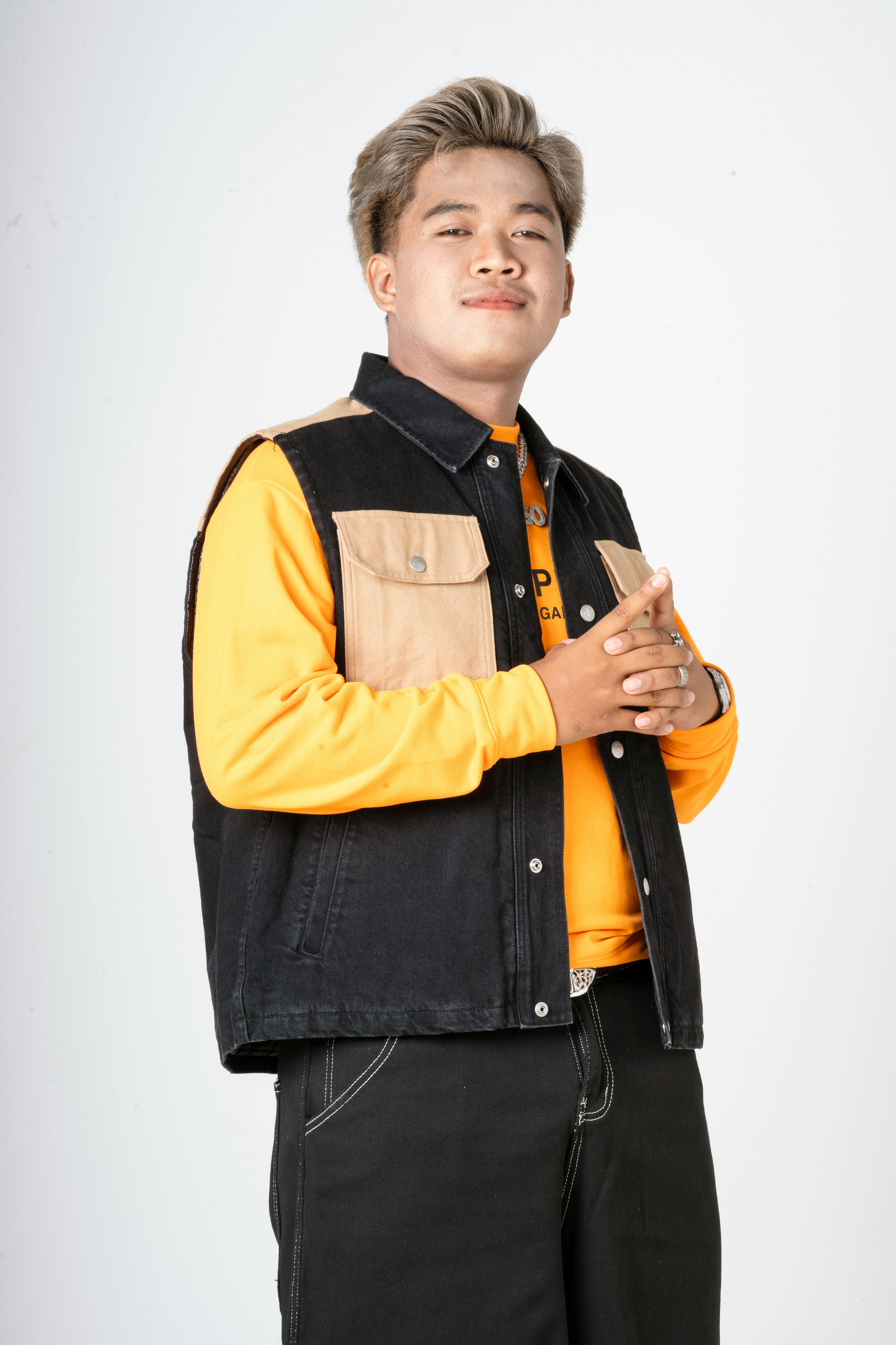 Portrait of a young man in casual fashion with denim vest and orange shirt, exuding confidence.