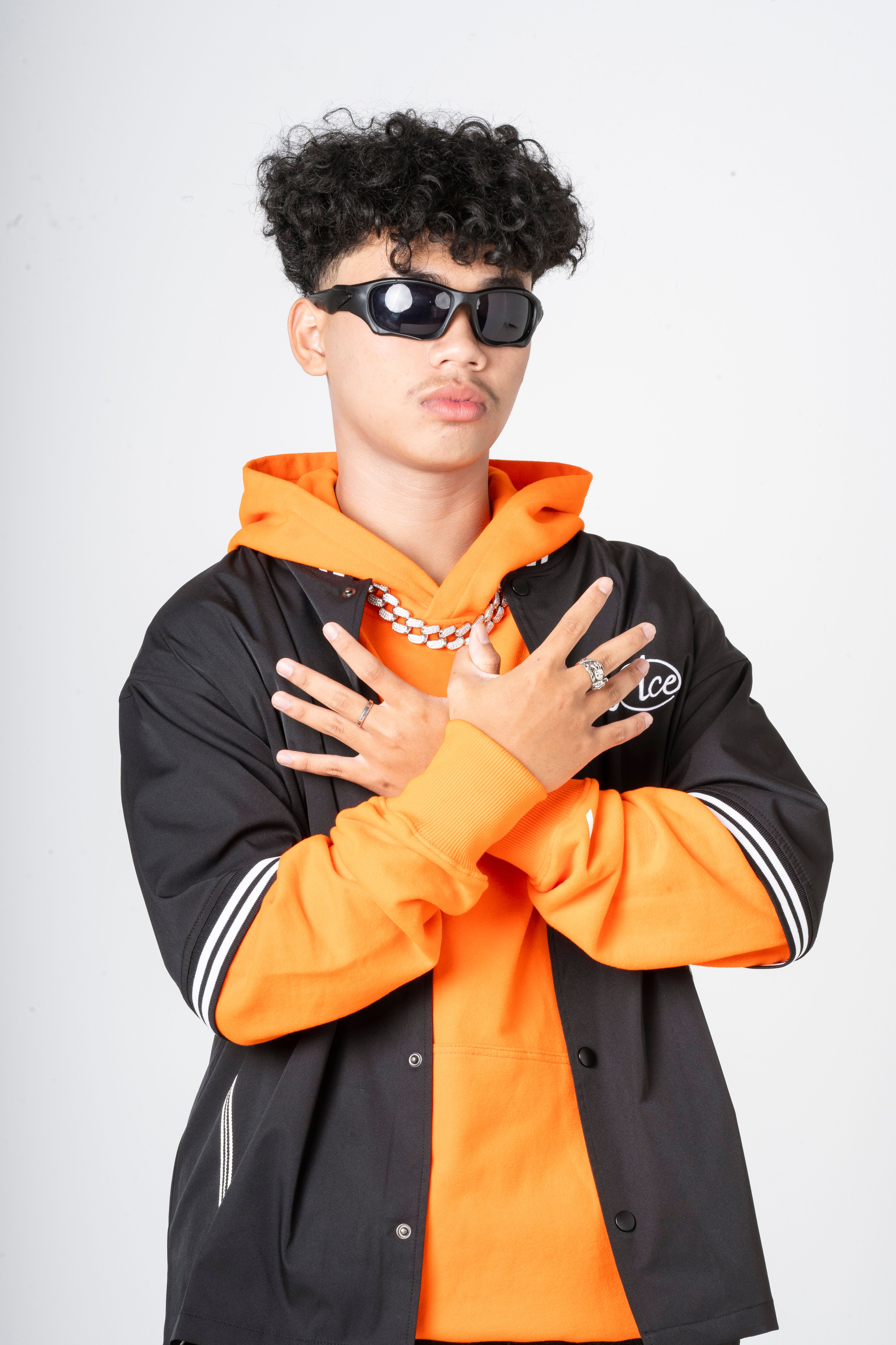 Stylish teenager in an orange hoodie and sunglasses, striking a pose.