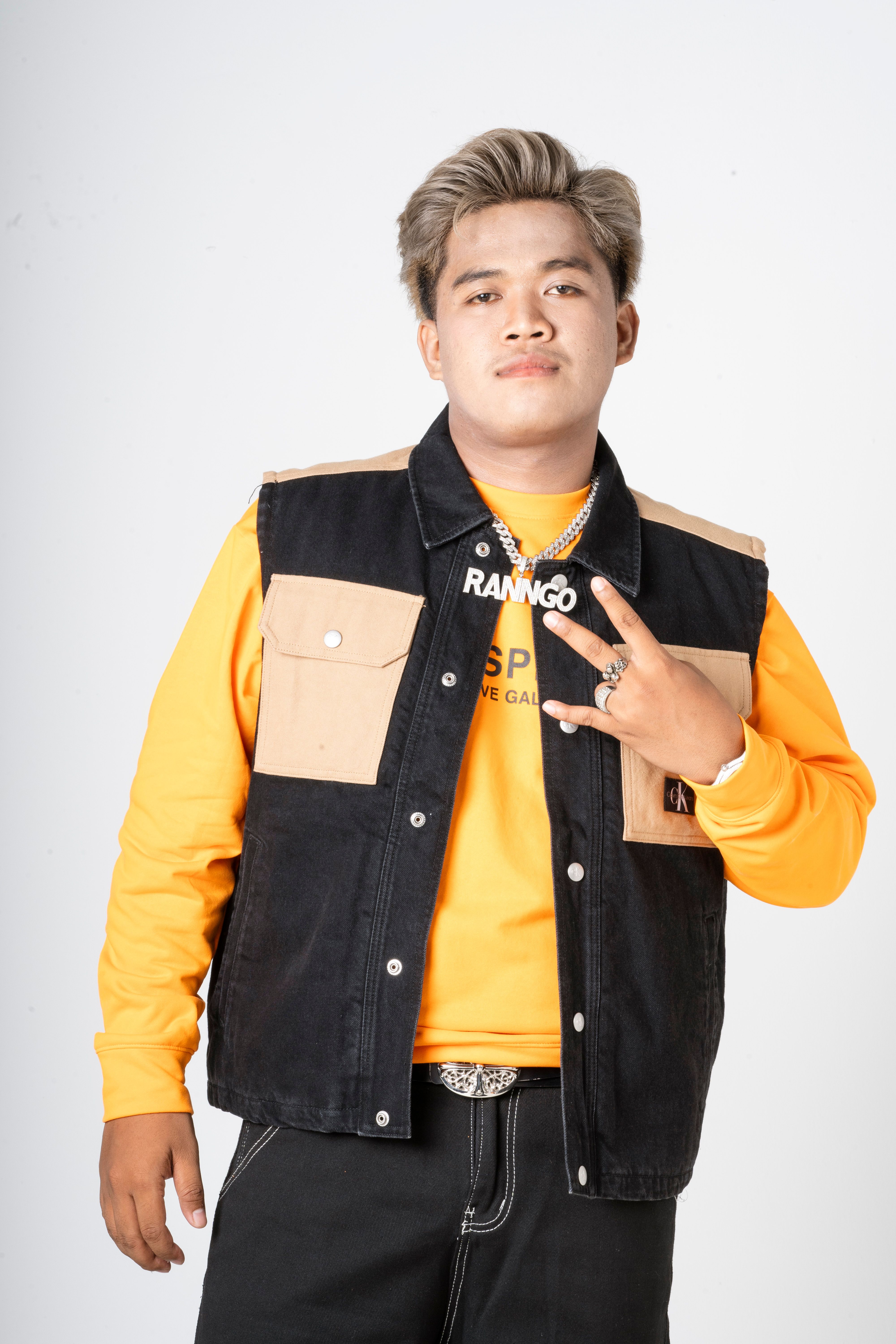 Young male adult in trendy streetwear posing confidently with peace sign.