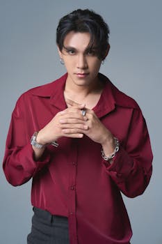 Confident young adult posing in a red shirt against a plain background.