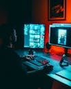 Man Editing Photos on Dual Monitors at Night