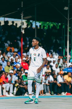 Professional basketball player in jersey during an outdoor game with a lively crowd.