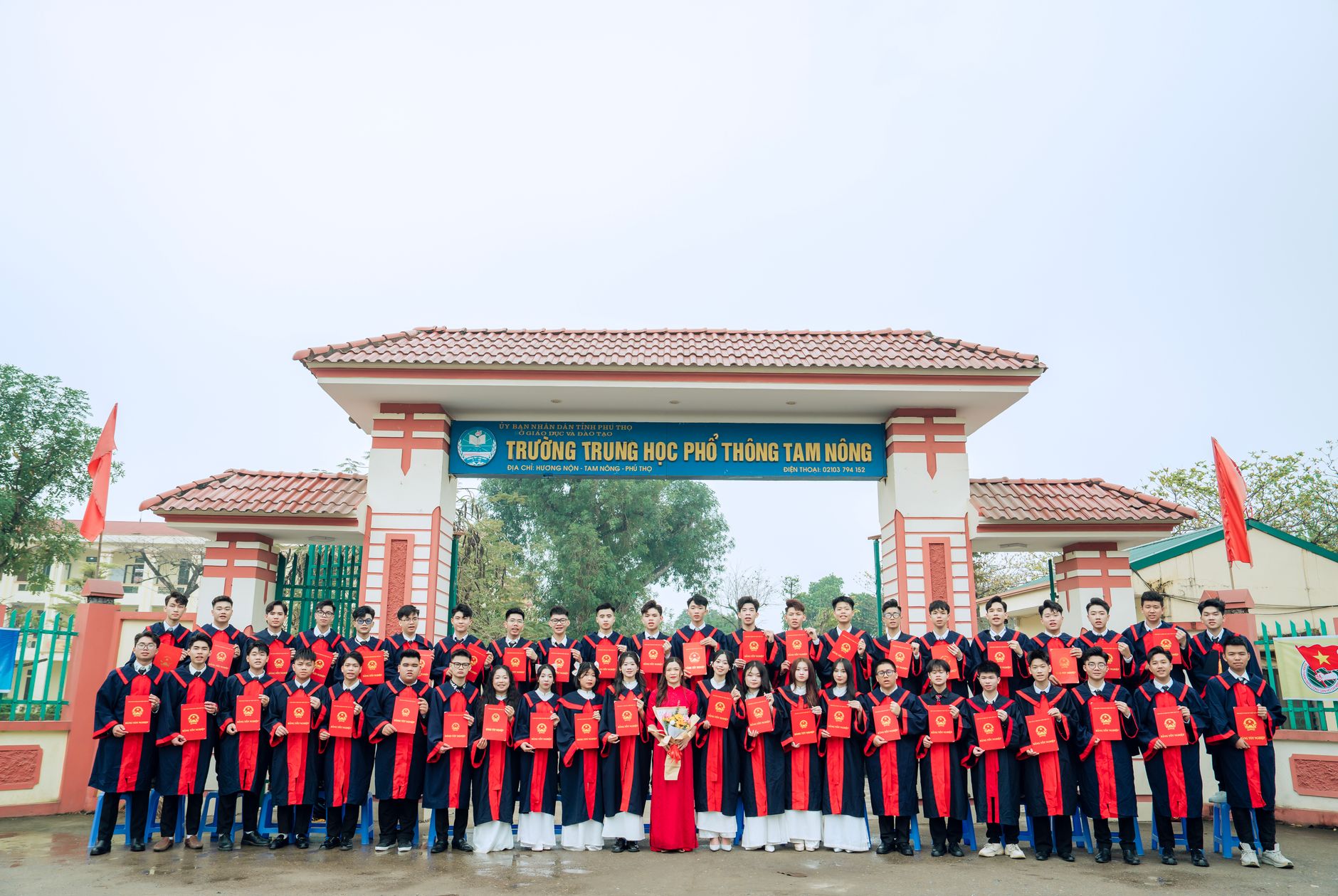 Graduating students pose with diplomas in front of Tam Nong High School in Vietnam.