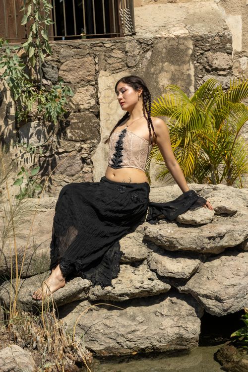 Free Serene woman sitting on rocks surrounded by natural elements, enjoying a sunny day. Stock Photo
