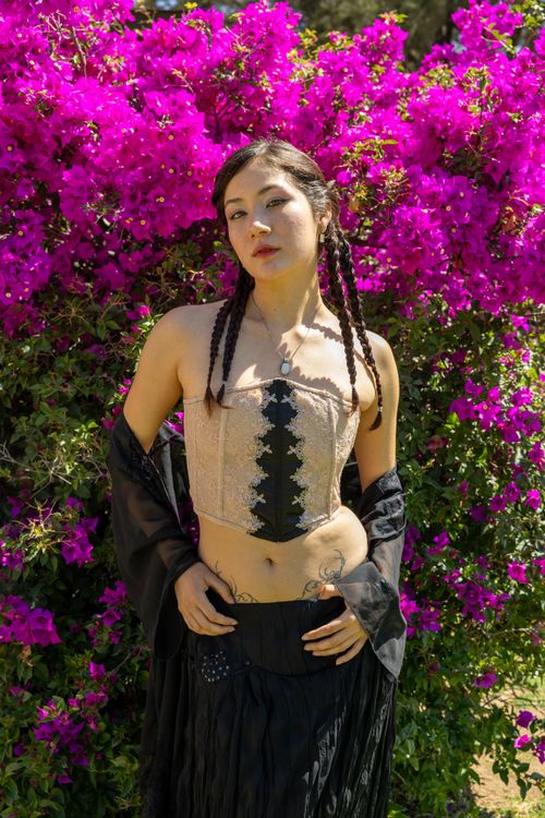 Free A stylish woman poses confidently in front of vibrant pink bougainvillea flowers, showcasing a blend of fashion and nature. Stock Photo