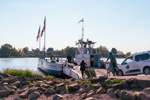 Free People with bicycles board a ferry on a calm river under a clear blue sky. Stock Photo