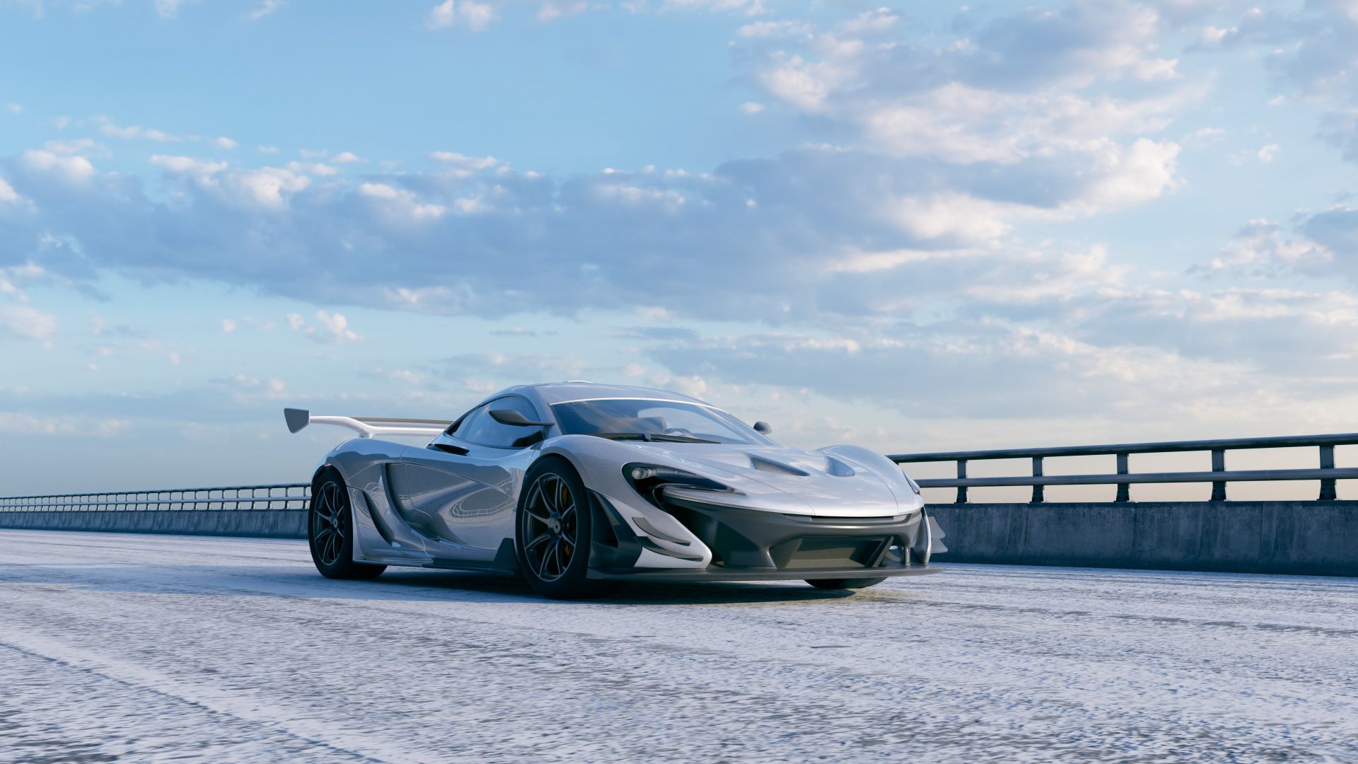 A sleek silver sports car drives on an empty highway under a clear blue sky.