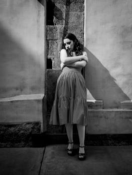 A contemplative woman leans against a weathered wall in Mexico City, captured in dramatic black and white.