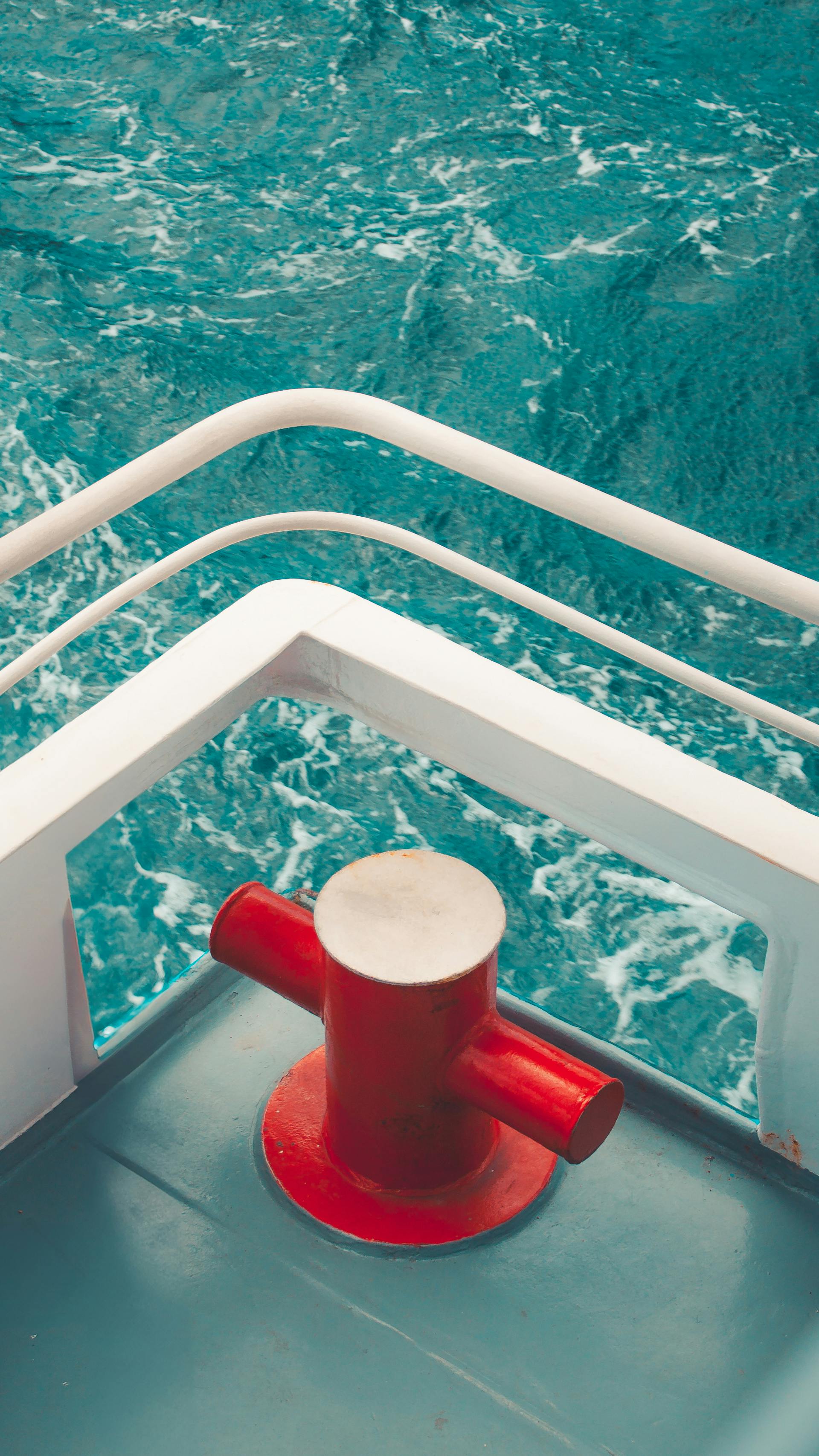 Free A vibrant red bollard on a ship deck overlooking the ocean's turquoise waves creates a striking maritime scene. Stock Photo