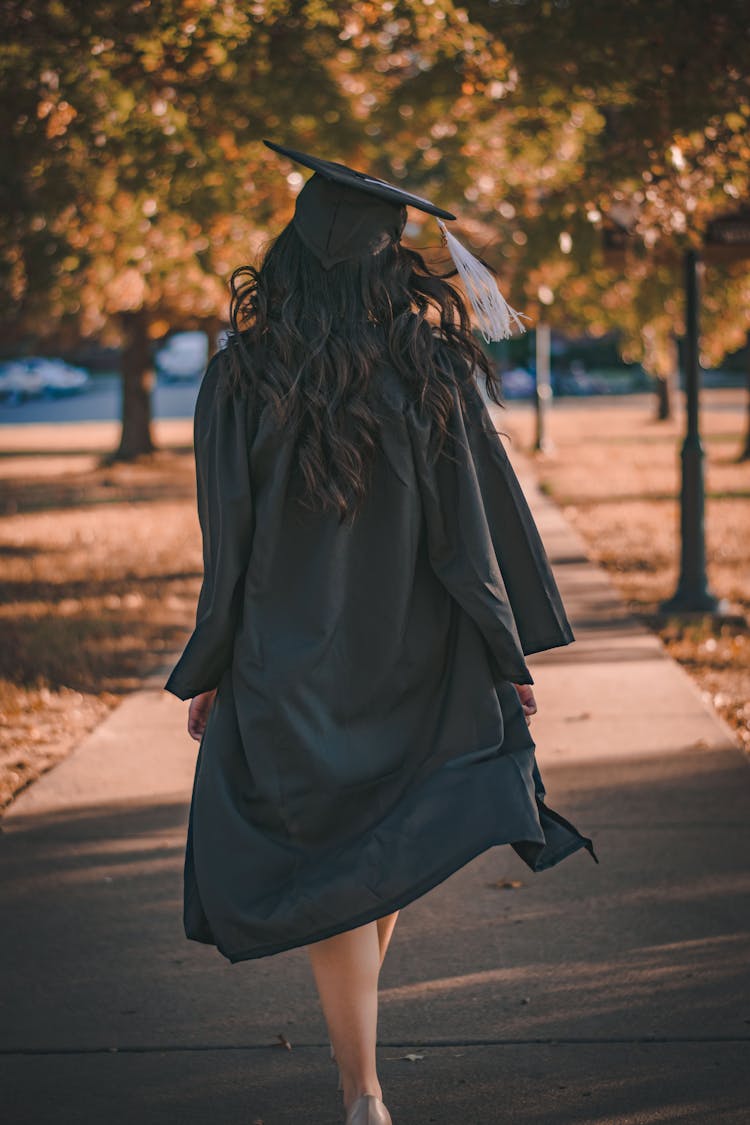 Woman In Black Long Sleeve Dress Standing On Brown Concrete Pathway