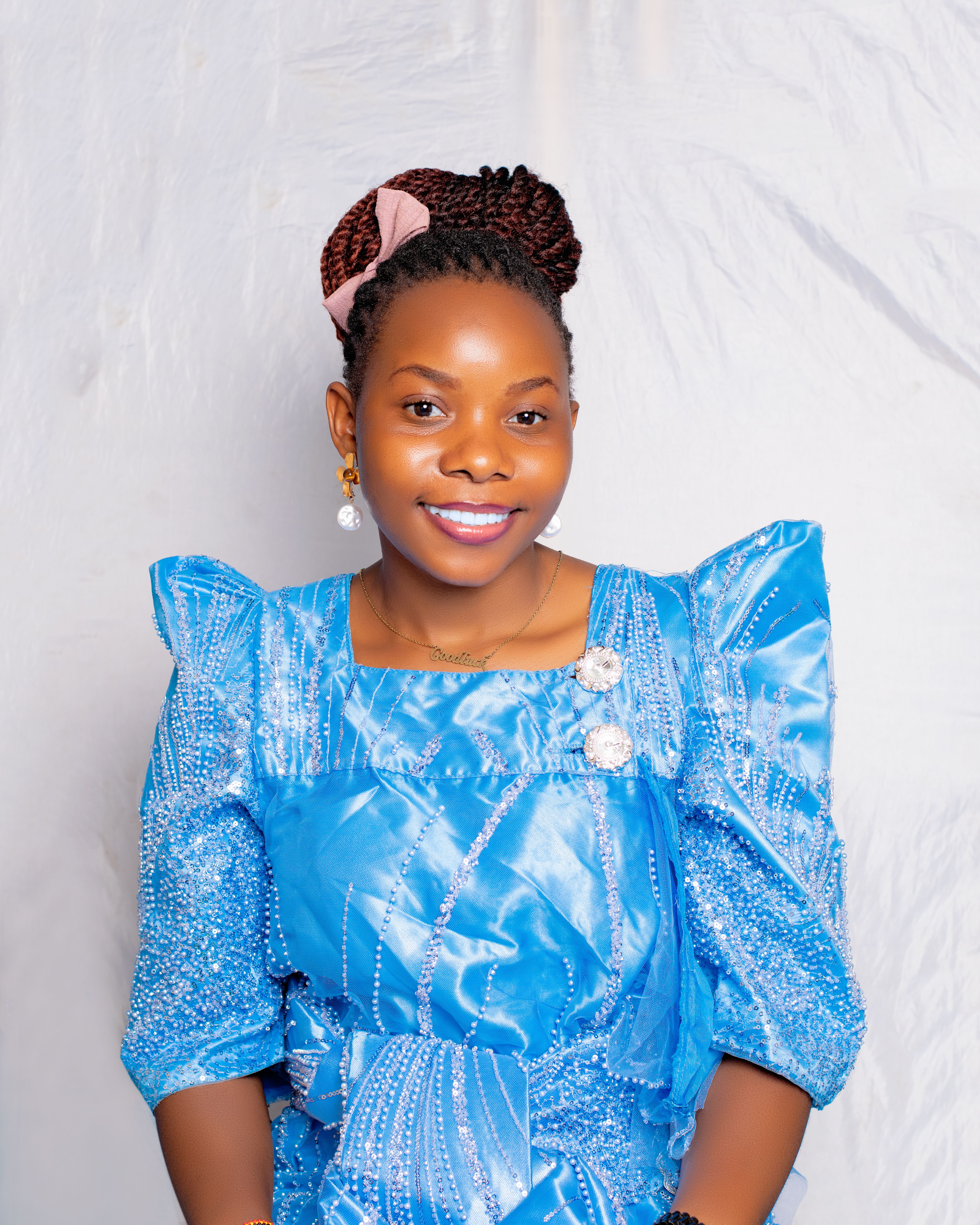 Smiling woman in a blue dress with intricate details, against a soft background.