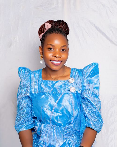 Free Smiling woman in a blue dress with intricate details, against a soft background. Stock Photo
