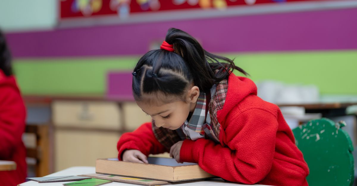 Une jeune fille absorbée par une activité créative à un bureau de classe coloré.