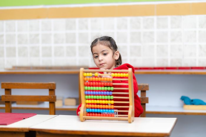 Young child focused on an abacus exercise in a bright classroom