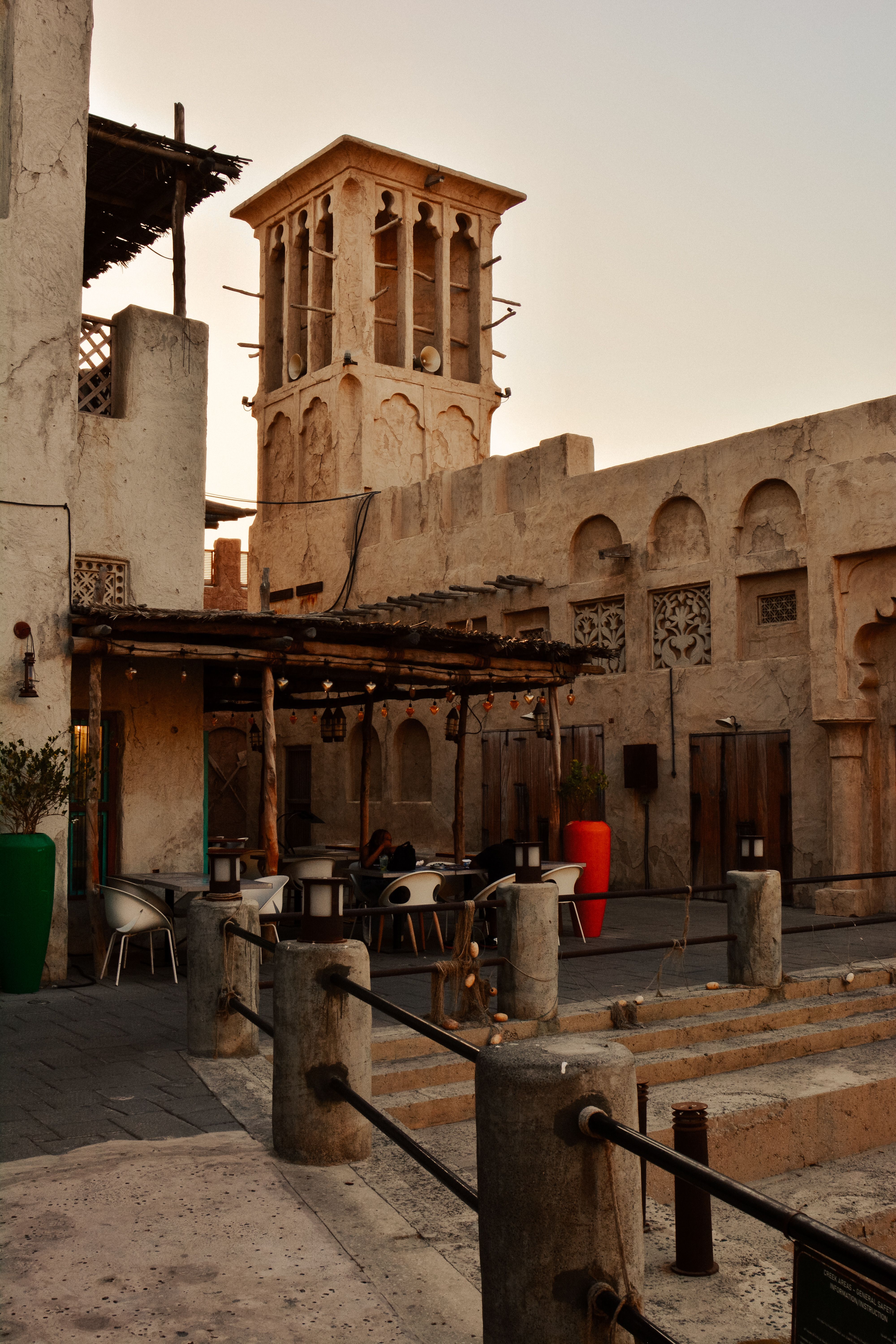 Scenic view of traditional Dubai architecture at sunset, highlighting its unique wind tower and courtyard.