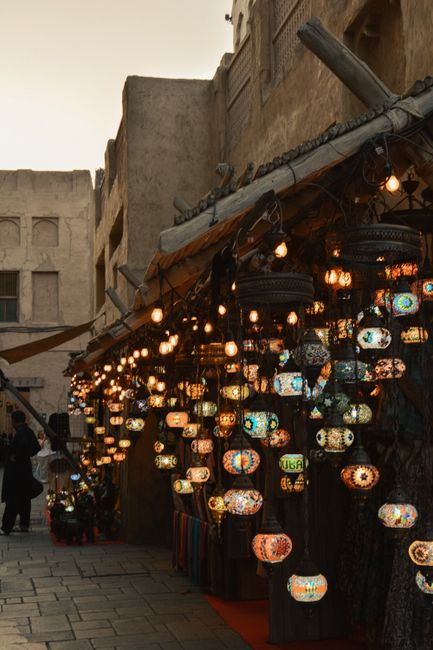 Beautifully lit traditional lanterns at a bustling Dubai market during dusk, capturing the city's vibrant essence.