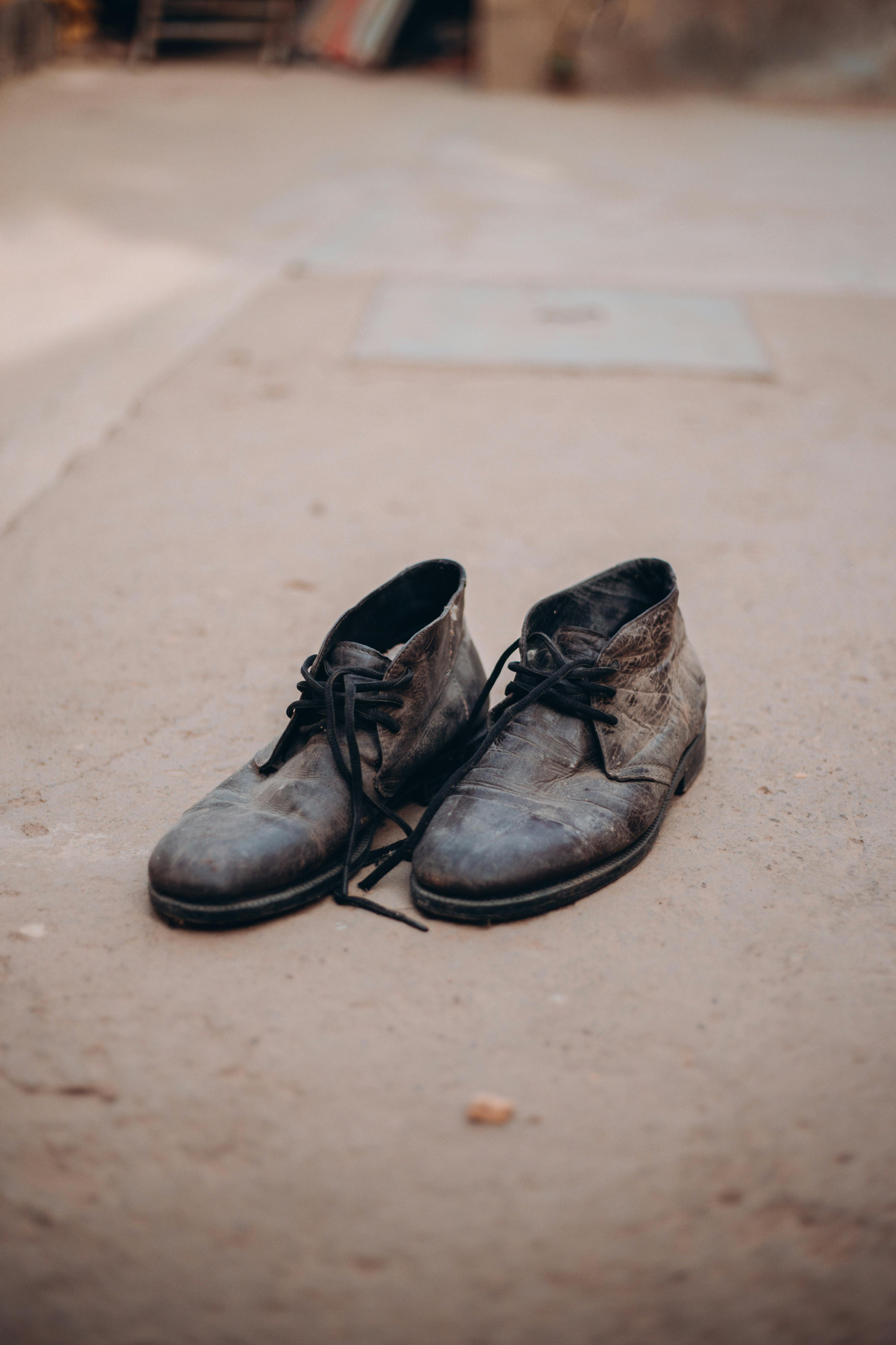 Close-up of old leather shoes on outdoor pavement, showcasing vintage style and wear.