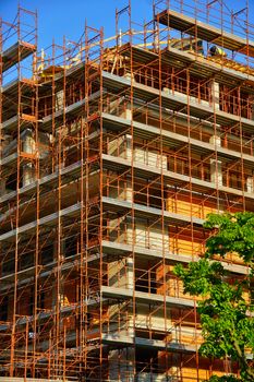 A multi-story building under construction with scaffolding on a sunny day.