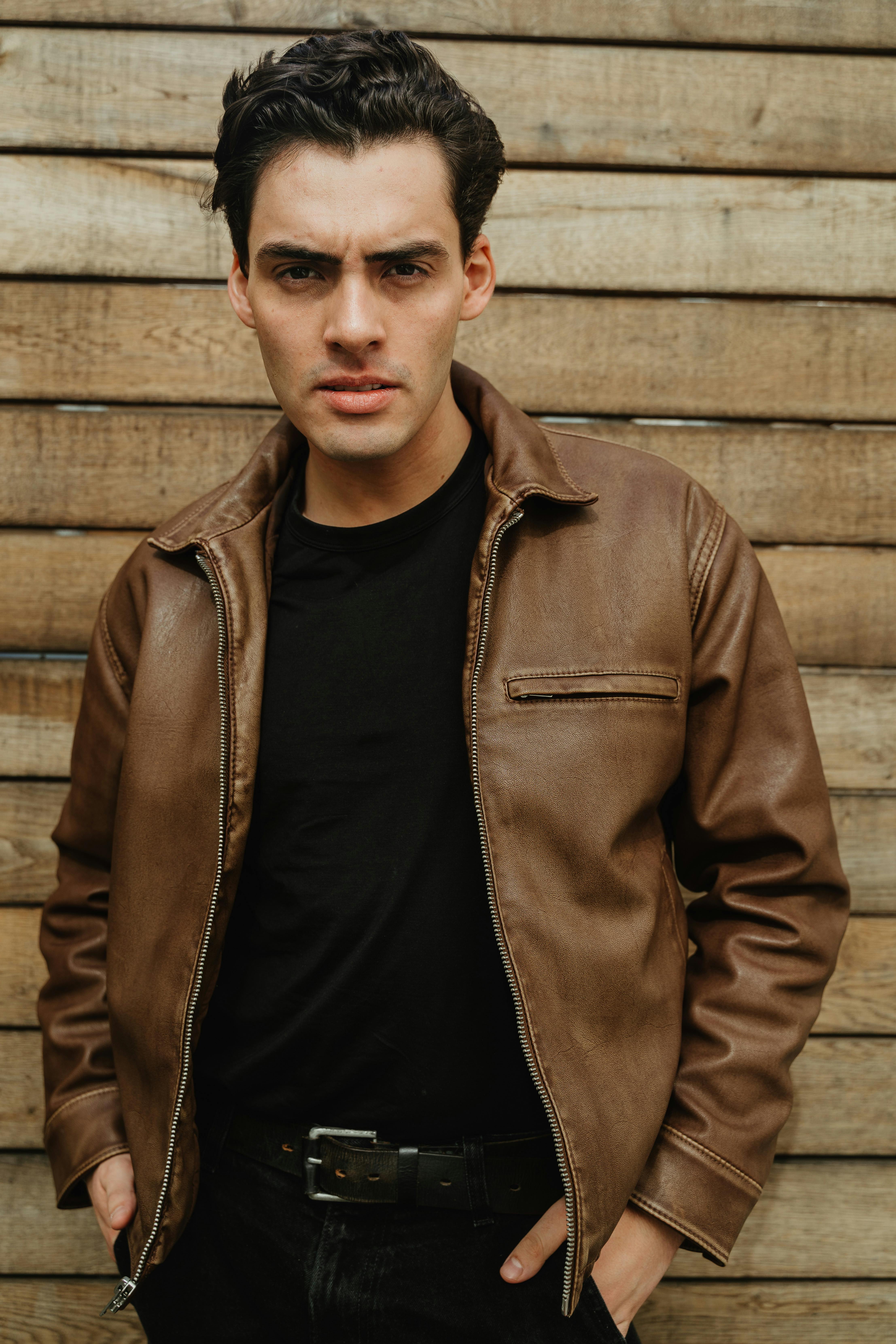 Outdoor portrait of a stylish male model posing against a wooden background in Berlin.