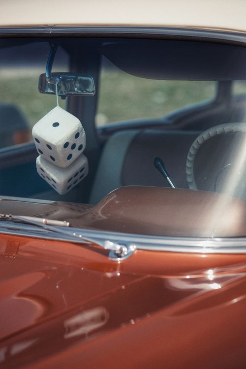 Free Vintage car interior featuring hanging fuzzy dice and a steering wheel. Stock Photo