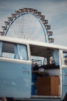 A ferris wheel seen behind an open retro van door, evoking a sense of adventure and nostalgia.