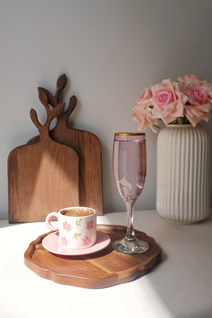 A stylish arrangement of a coffee cup, glass, and flowers in soft natural light, creating a cozy feel.