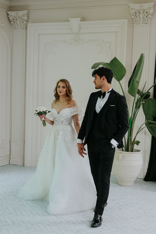 Free A bride and groom in elegant wedding attire in a beautifully decorated room. Stock Photo