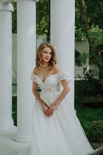 Beautiful bride in floral lace wedding dress posing outdoors with classic columns.