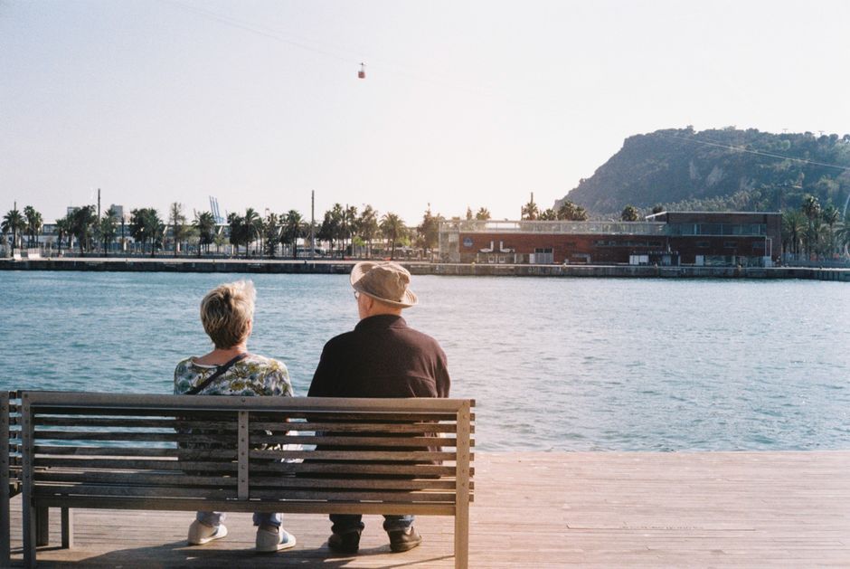 Una pareja de ancianos disfruta de un momento pacífico junto al agua en Barcelona.