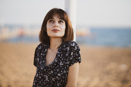 海滩边，一位穿着花卉连衣裙的年轻女子若有所思地抬头仰望