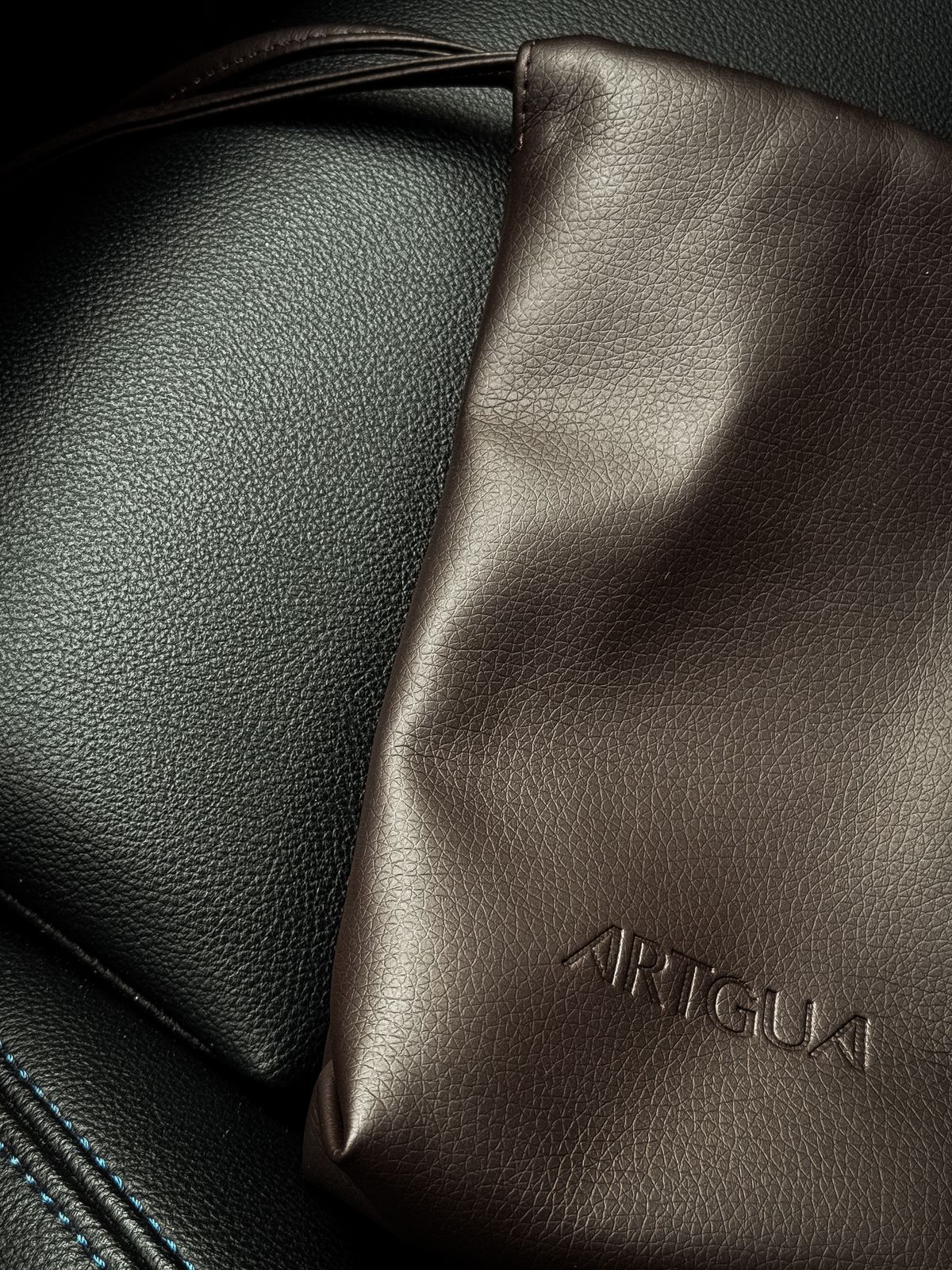 Close detail of a brown leather bag on a dark leather surface