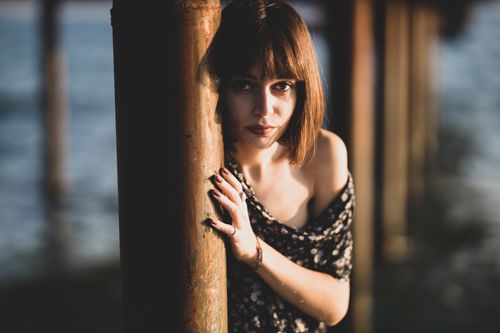 Free Stylish woman posing by a lakeside pier with soft lighting and fashion-forward attire. Stock Photo